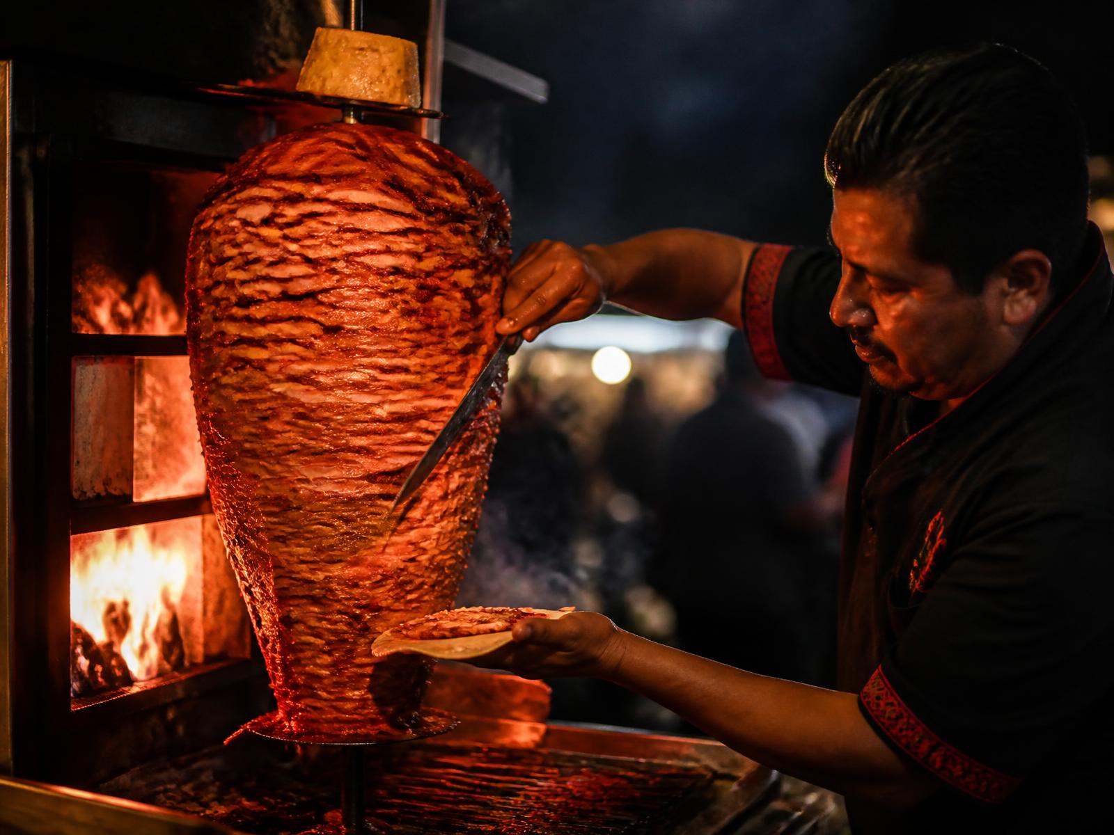 Taquero cortando carne del trompo de pastor